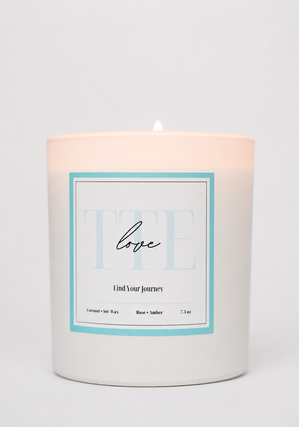 A white glass jar candle with a lit wick, featuring a minimalist white label with a light blue border and the word 'love' in script, on a clean white background.